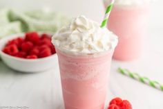 two drinks with whipped cream and raspberries in the background