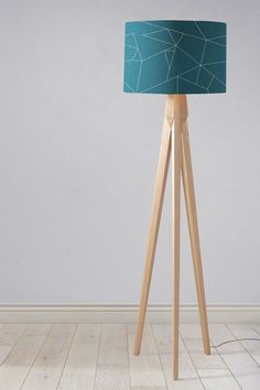 a wooden floor lamp with a blue shade on it's side and a white wall in the background