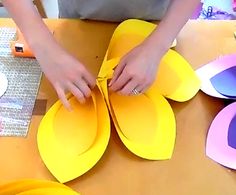 a person cutting out paper flowers on a table with other crafting supplies around them