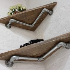 two wooden shelfs with metal pipe handles on the wall next to a flower pot