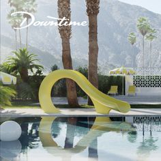 a yellow slide sitting in the middle of a swimming pool next to palm trees and mountains