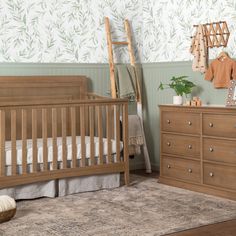 a baby's room with green wallpaper and wooden furniture