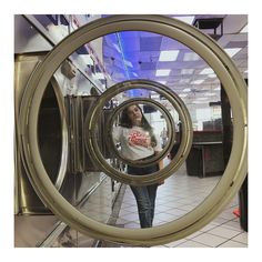 a woman standing in front of a dryer looking at her reflection through the door