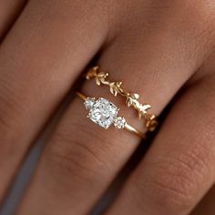 a woman's hand with an engagement ring on top of her finger and the other hand holding it