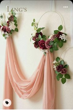 two flowers are hanging on the wall next to some draping and greenery