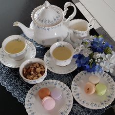 a table topped with plates and bowls filled with food next to cups full of tea