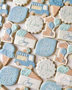 decorated cookies with blue and white frosting are arranged on a tablecloth that says happy ice cream day