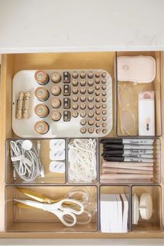 the drawer is organized with various items such as pens, scissors and other office supplies