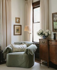 a living room filled with furniture next to a window covered in drapes and curtains