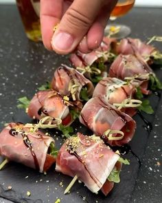 a person is picking up some food on a black plate with toothpicks and garnishes