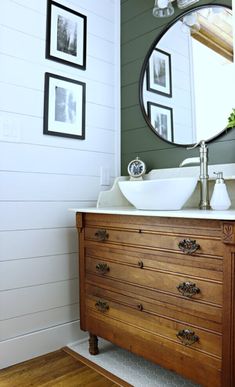 a bathroom with a sink, mirror and pictures on the wall above it's drawers