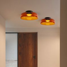 two lights that are on the ceiling in a room with white walls and wood doors