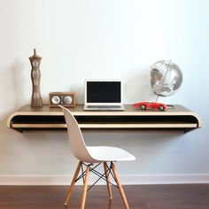 a laptop computer sitting on top of a wooden desk next to a white chair and clock