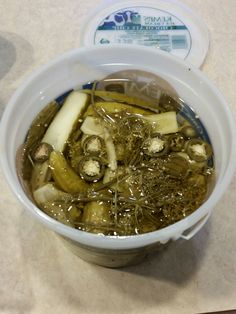 a white bowl filled with green vegetables on top of a counter next to a plastic container