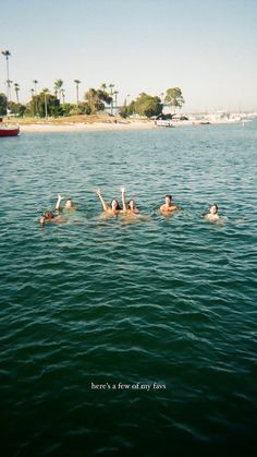 four people floating in the water with their arms up