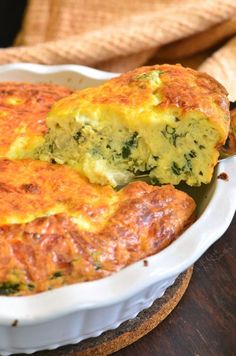 a casserole dish with broccoli and cheese in it on a wooden table