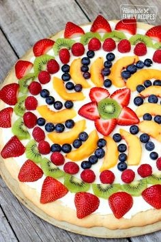 a pizza with fruit on it sitting on top of a wooden table