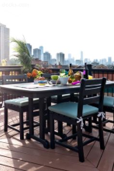 an outdoor table and chairs on a deck overlooking the city