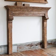 an old wooden fireplace surround in a room with white walls and wood flooring on the side