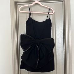 a black dress hanging on a door with a bow at the front and back side