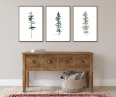 three paintings on the wall above a wooden table with a basket and rug in front of it