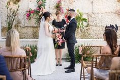 a bride and groom are getting married in front of an outdoor ceremony with pink flowers