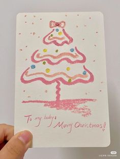 a hand holding up a card with a christmas tree drawn on it and the words to my baby merry christmas