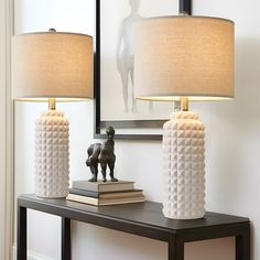 two lamps sitting on top of a wooden table next to a framed photo and a mirror