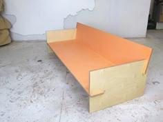 an orange bench sitting on top of a white floor next to a pile of boxes