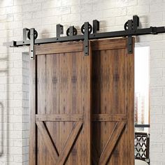 an open wooden door with metal hardware on the top and bottom, in front of a white brick wall