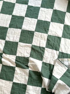 a green and white checkered quilt laying on top of a bed