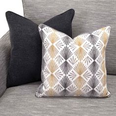 two black and white pillows sitting on top of a gray couch