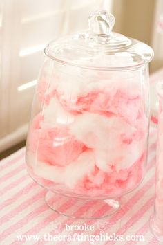 pink and white cotton floss in a glass jar on a striped tablecloth next to cups