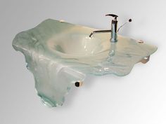 a bathroom sink that is made out of glass and has a faucet in it