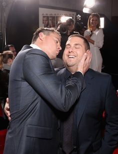 two men in suits are touching each other's face at the same time,