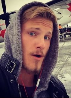 a man with ear buds standing in front of an airplane