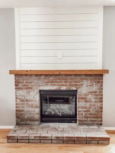 a brick fireplace with white painted walls and wood trim around the mantel above it