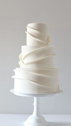 a three tiered white wedding cake on a pedestal