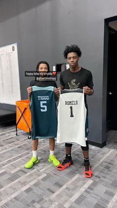 two young men holding up jerseys in front of a sign that says tuco and ronald