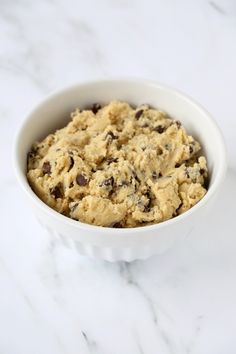 a white bowl filled with cookie dough on top of a marble counter