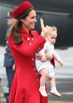 a woman in a red coat holding a baby