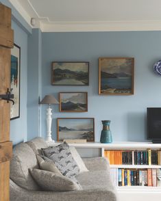 a living room with bookshelves and pictures on the wall above it's couch