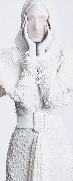 a mannequin dressed in white holding her hands up to her face