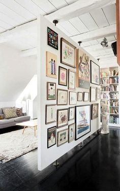 a living room filled with lots of pictures on the wall next to bookshelves