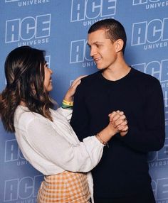 a man and woman standing next to each other in front of a blue wall with the words ice on it