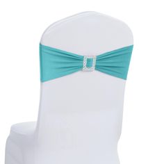 the back of a white chair with a turquoise sash and diamond buckle at the top