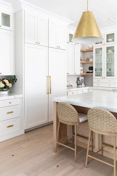 a kitchen with white cabinets and gold pendant light hanging from the ceiling over the island