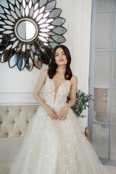 a woman standing in front of a mirror wearing a wedding dress with flowers on it