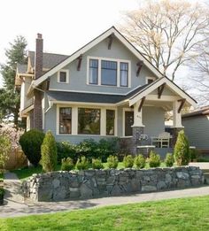 a gray house with white trim and lots of trees in the front yard is shown