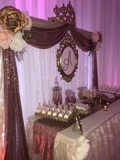 a table topped with lots of desserts under a purple and white drape covered wall